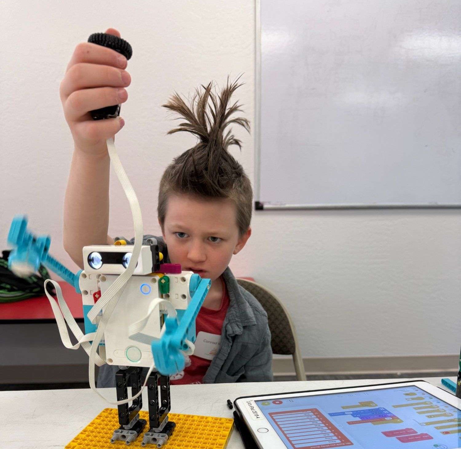 Student holding up LEGO robot with pure joy at PATH